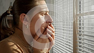 Stressed and afraid woman closing her mouth while being witness of crime or catastrophy through window