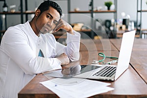 Stressed African American black man doctor looking at laptop reading bad news online