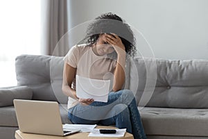 Stressed african woman holding bills worried about bankruptcy bank debt