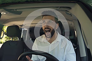 Stressed angry man in driver`s seat of modern car, view through windshield