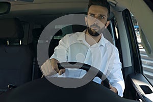 Stressed angry man in driver`s seat of modern car, view through windshield