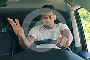 Stressed angry man in driver`s seat of modern car, view through windshield