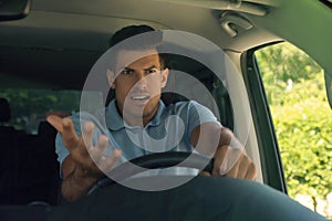 Stressed angry man in driver`s seat of modern car, view through windshield