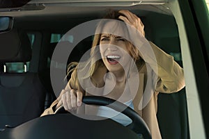 Stressed angry woman in driver`s seat of modern car, view through windshield