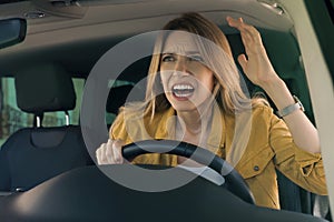 Stressed angry woman in driver`s seat of modern car, view through windshield