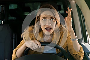 Stressed angry woman in driver`s seat of modern car, view through windshield
