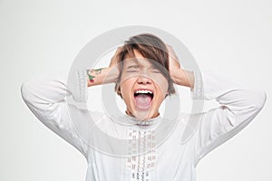 Stressed angry young woman holding head by hands and screaming