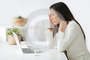 Stressed asian businesswoman having headache or migraine at work