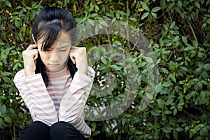 Stressed asian child girl covering ears with fingers because of loud noise,fear of noise,feel panic, anxiety female people having