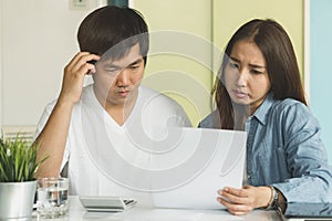 Stressed asian couple looking at issues notification from bank about late payment home loan credit