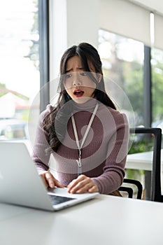 A stressed Asian female worker is having a problem installing programs on her laptop