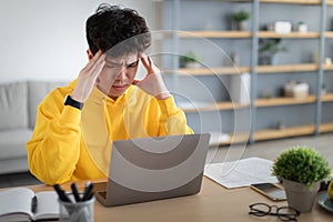 Stressed Asian male sitting at desk with pc