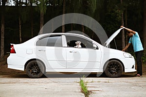 Stressed asian man looking at the engine of broken car with his