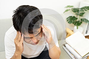 Stressed asian middle-aged man suffering from headache or symptoms of migraine attack,aching pain touch his head,massage the photo