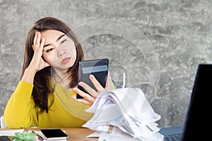 Stressed Asian woman hand holding calculator looking at the nuber of debt payment for unpaid financial bills with sad face ,payday