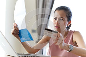 Stressed Asian woman holding credit card and bills feeling worry about her debt.