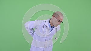 Stressed bald multi ethnic man doctor having back pain