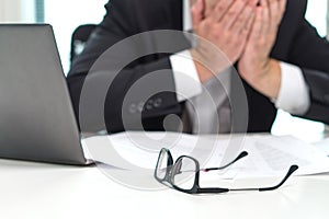 Stressed business man covering face with hands in office.