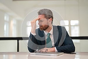 Stressed business man having headache at office. Tired businessman is working overtime and has headache. Overworked man