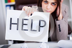 Stressed business woman imploring for help, holding a cardboard