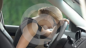 Stressed business woman lying on steering wheel, depression, work problems