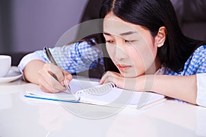 Stressed business woman sitting at her desk and writes a note on