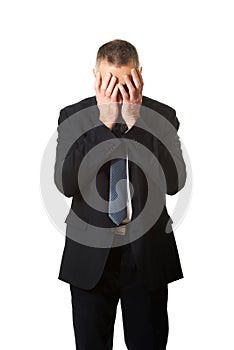 Stressed businessman covering his face with hands