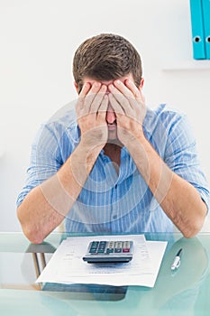 Stressed businessman covering his face at his desk