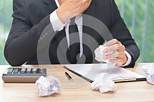 Stressed businessman crumple paper with calculator and contract