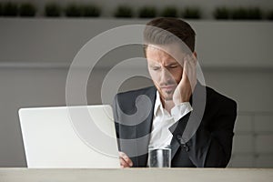 Stressed businessman having bad headache at work.