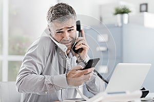 Stressed businessman having multiple calls photo