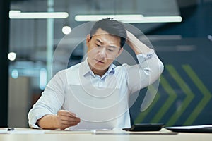 Stressed businessman holding face with his hands because having trouble. Bankrupt Asian Male is sitting with laptop