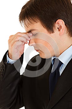 Stressed businessman holding fingers at noseband