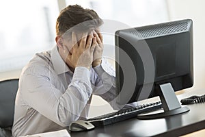 Stressed Businessman Leaning On Computer Desk