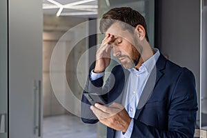 Stressed businessman reading bad news on smartphone