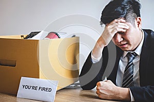 Stressed businessman receive fired letter from company and packing belongings and files into brown cardboard box, changing and