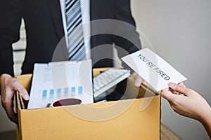 Stressed businessman receive fired letter from employer and packing belongings and files into brown cardboard box, changing and
