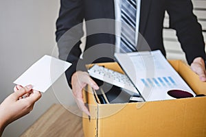 Stressed businessman receive fired letter from employer and packing belongings and files into brown cardboard box, changing and