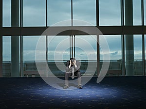 Stressed Businessman sitting alone in room head in hands