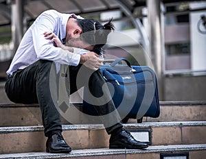 Stressed businessman sitting at stairway outdoor.Bankrupt businessman sitting outdoor.