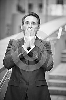 Stressed businessman standing outdoors with his hands covering his face