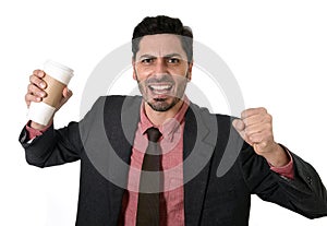 Stressed businessman in suit and tie crushing empty cup of take away coffee in caffeine addiction concept