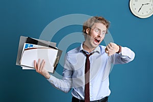 Stressed businessman trying to meet deadline on color background