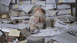 Stressed businessman under a lot of paperwork