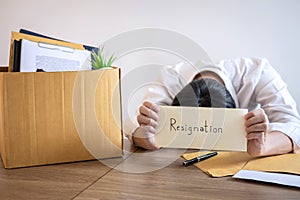 Stressed businessman will being resignation and packing belongings company and files into brown cardboard box, changing and