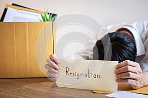 Stressed businessman will being resignation and packing belongings company and files into brown cardboard box, changing and