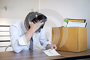 Stressed businessman will being resignation and packing belongings company and files into brown cardboard box, changing and