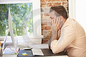 Stressed Businessman Working At Computer In Modern Office