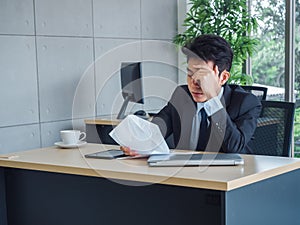 Stressed businessman. Young Asian business man in suit feeling down and tired