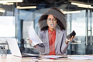 Stressed businesswoman with paperwork and smartphone in office